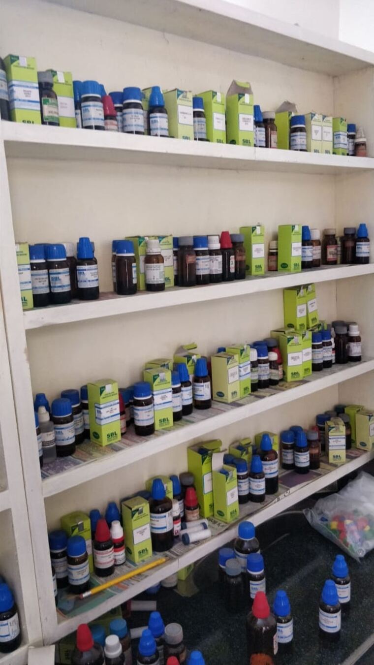 Close view of homeopathic remedy bottles and boxes arranged on the dispensary shelves.